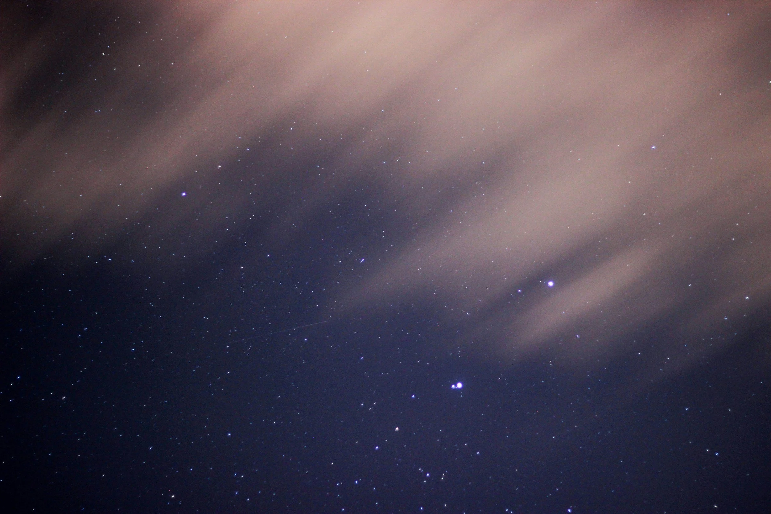 Night sky filled with stars and some clouds.
