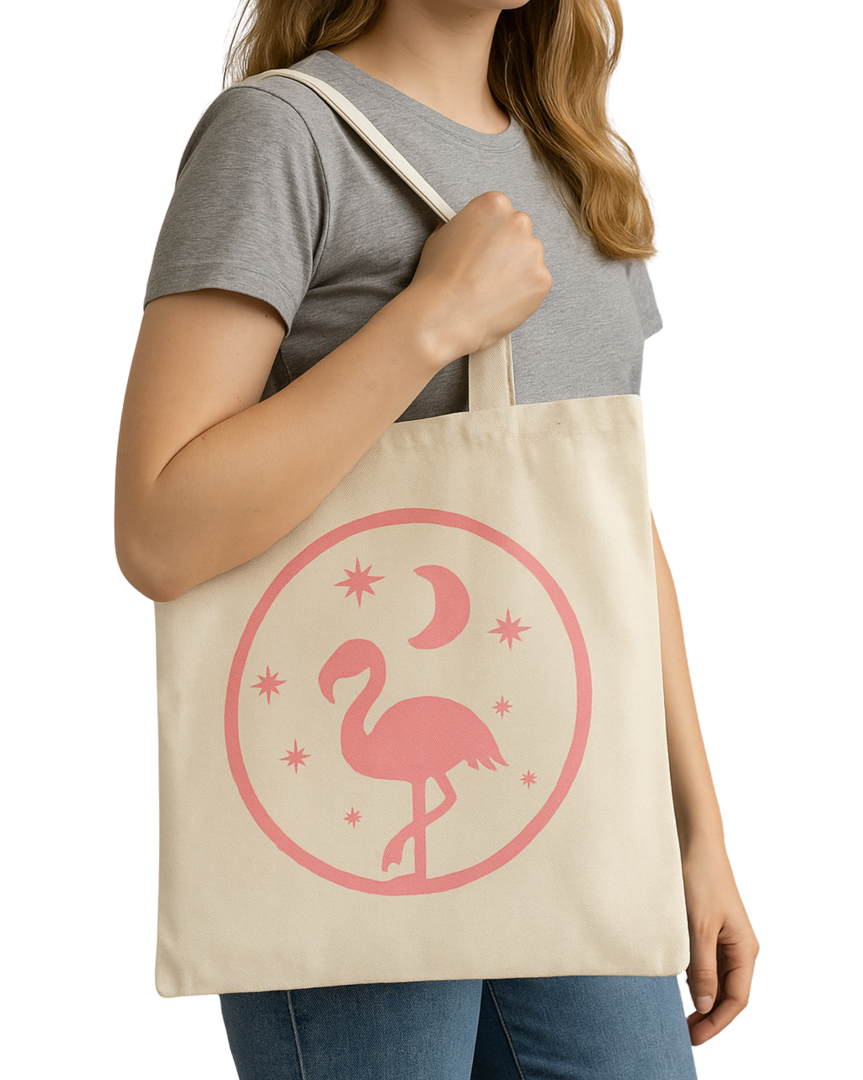 Person holding a beige tote bag with a pink flamingo, moons, and stars printed on it.