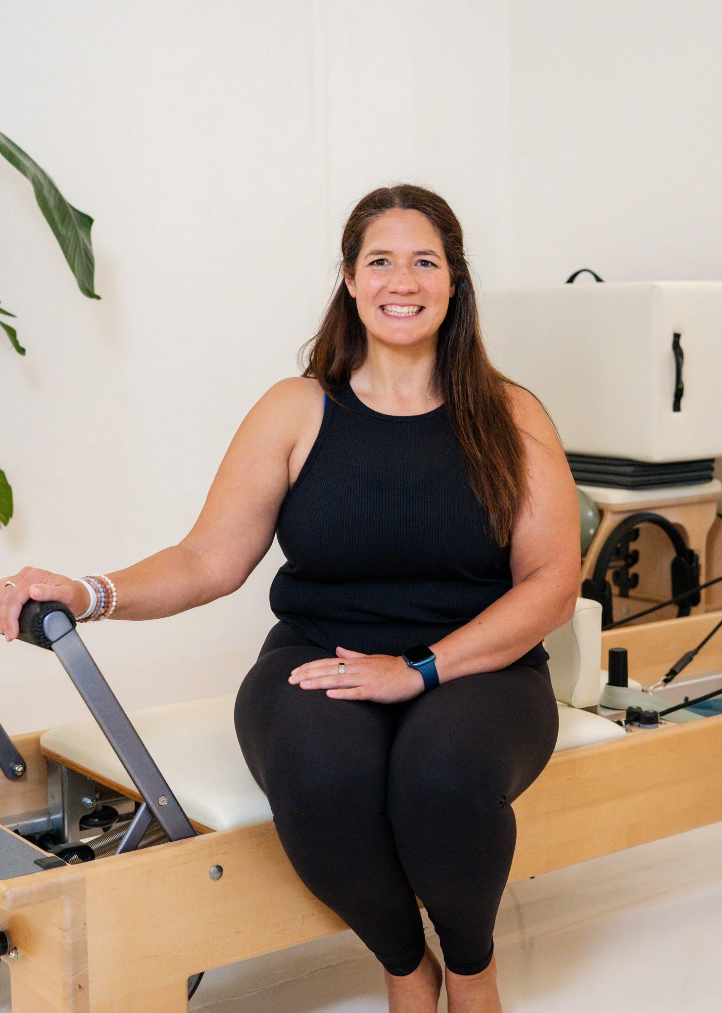 Smiling person in a black sweatshirt with "PARADISE PLANT" text, standing indoors with modern decor and a plant.