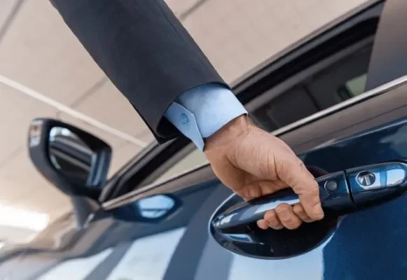 Cliente abriendo la puerta de un automóvil reluciente gracias al servicio rápido de gestoría vehicular