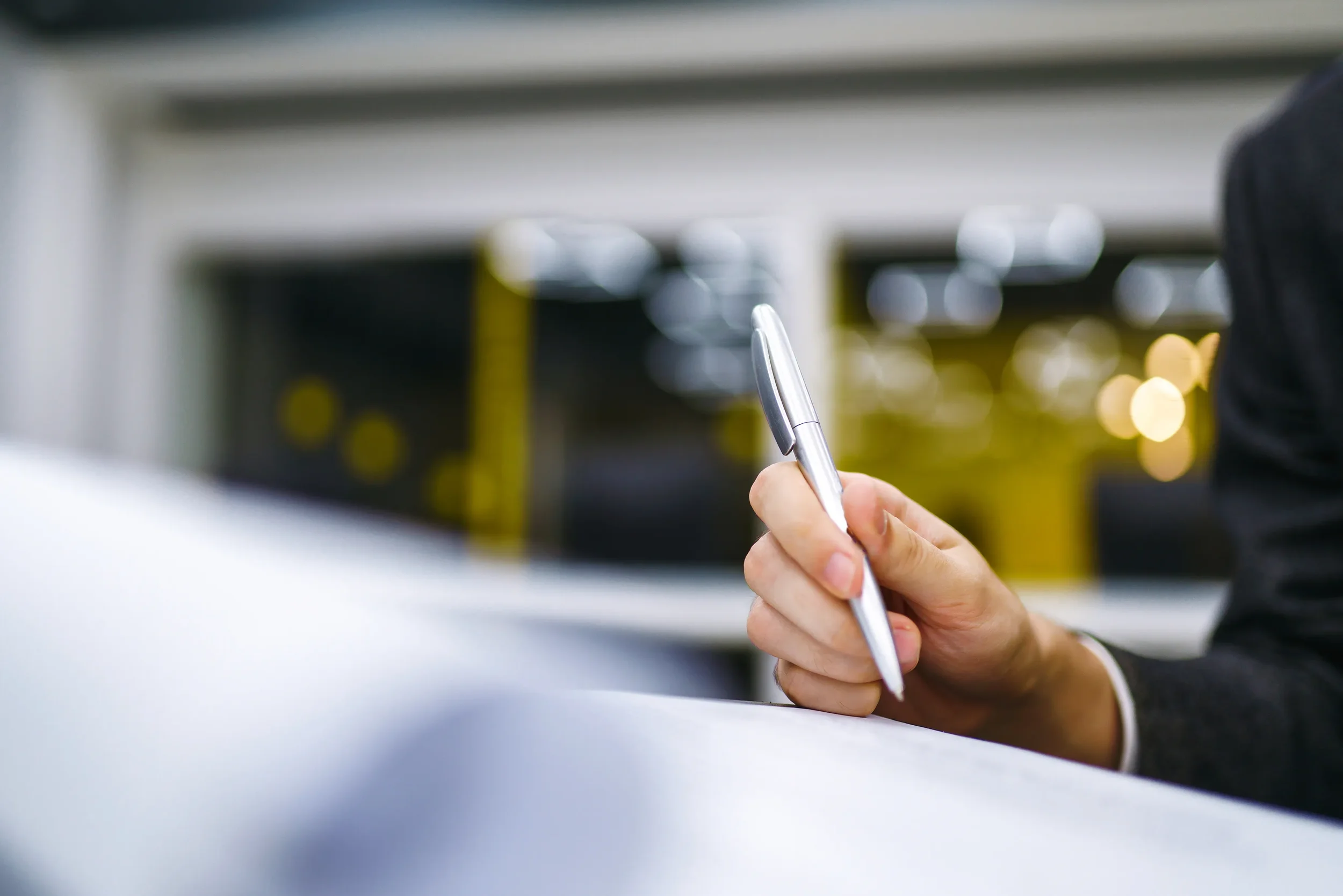 Primer plano de mano con bolígrafo lista para firmar la papelería legal de la regularización vehicular.