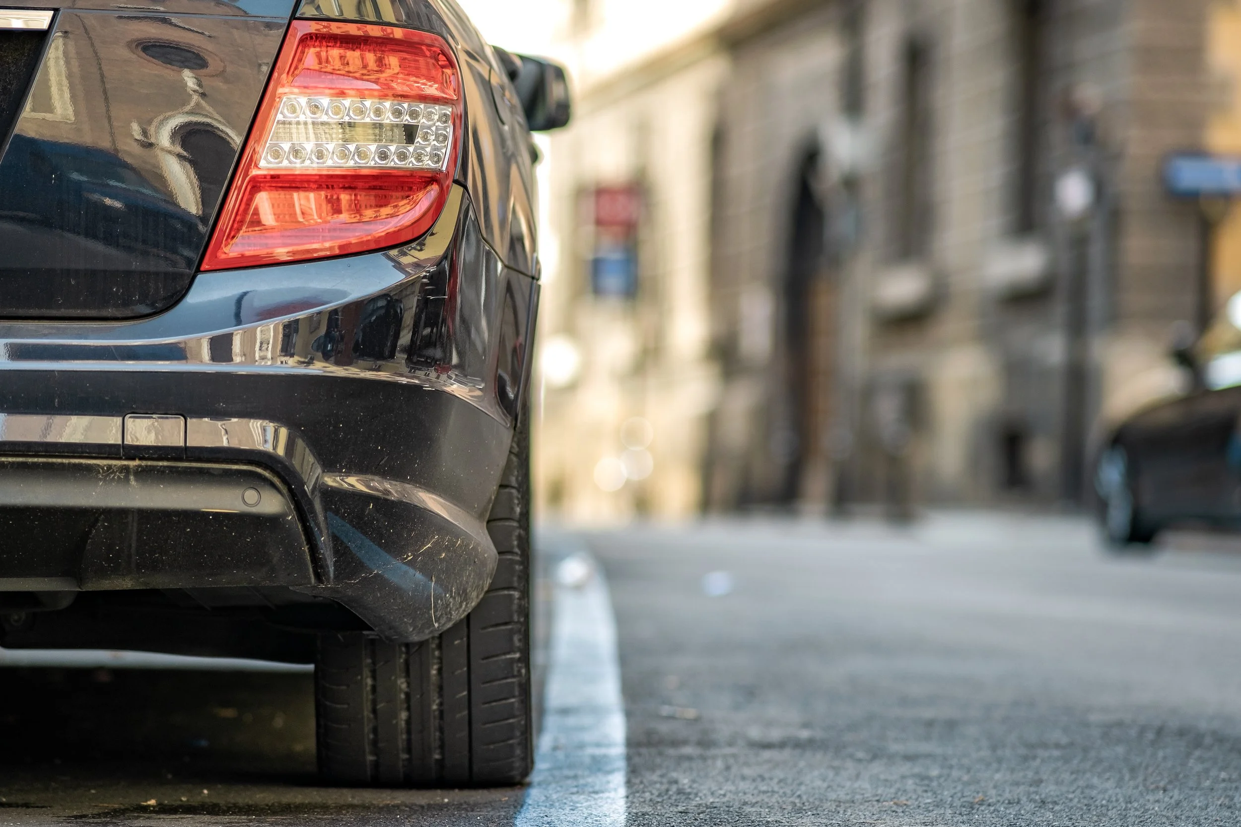 Detalle de la parte trasera de un coche oscuro en la ciudad tras completar el proceso de cambio de placas de circulación.