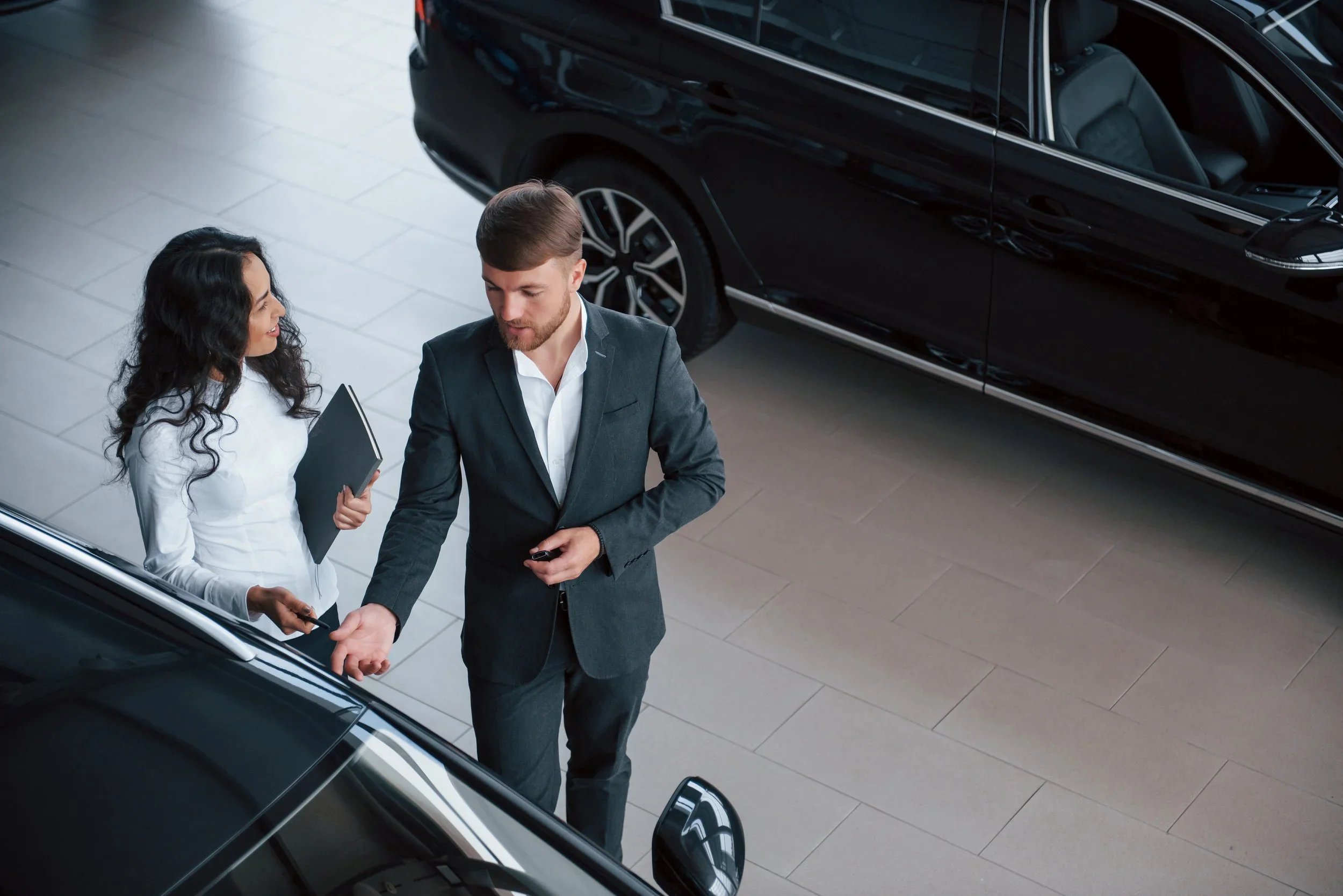 Asesores comerciales firmando un acuerdo de adquisición y servicios para flotillas de autos de empresas en agencia.