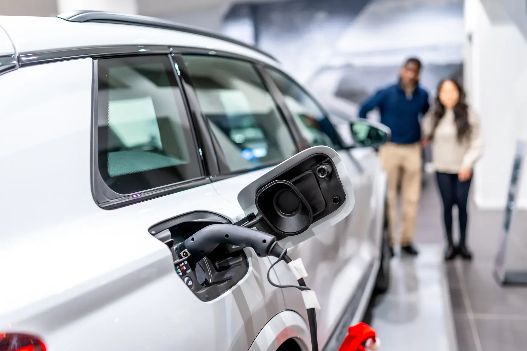 Pareja recibiendo información sobre cómo realizar los trámites de placas para auto eléctrico tras comprar un vehículo.