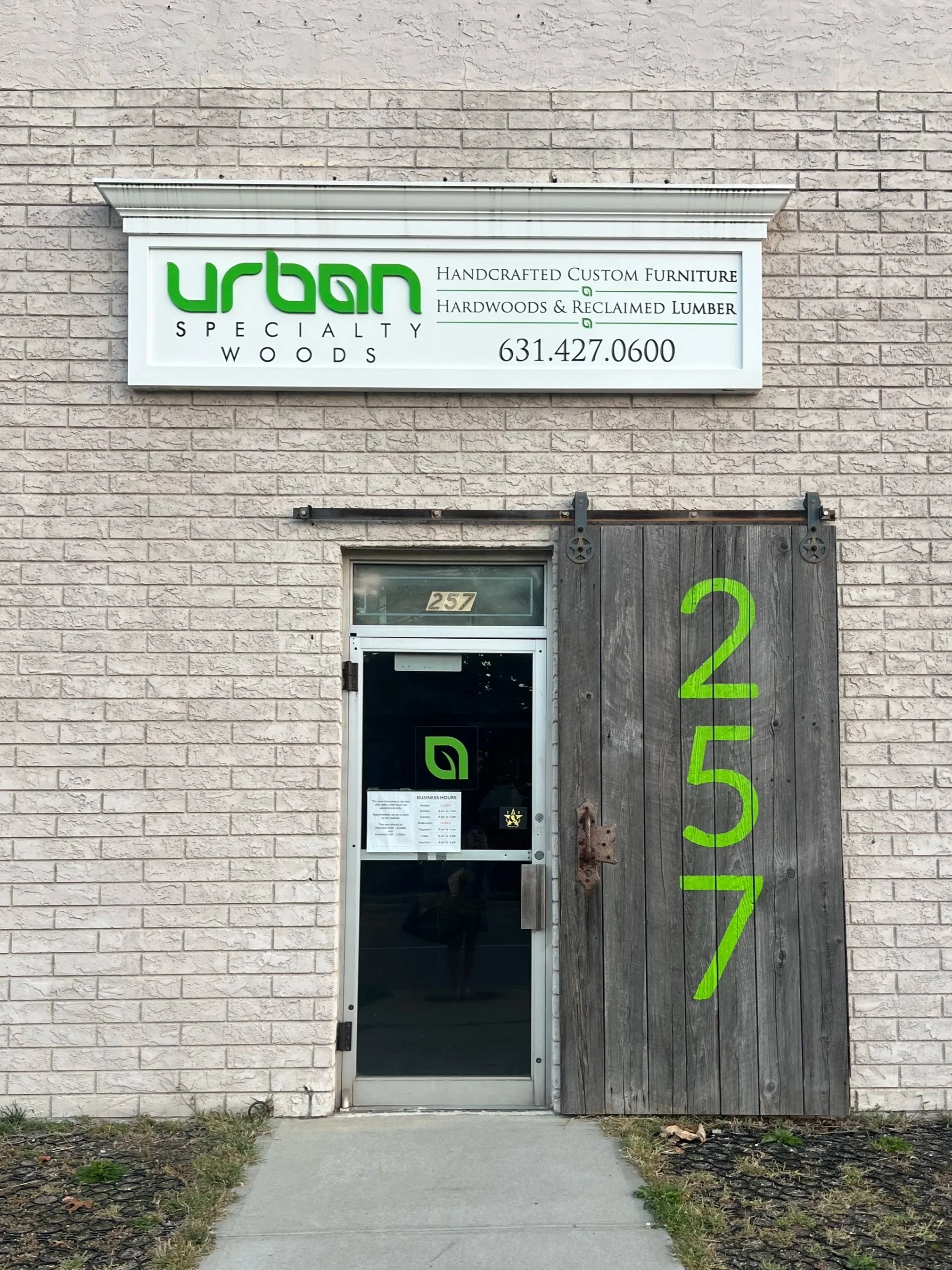 Outside front door of Urban Specialty Woods. Barn door painted with the number 257. White sign with phone number above the door.