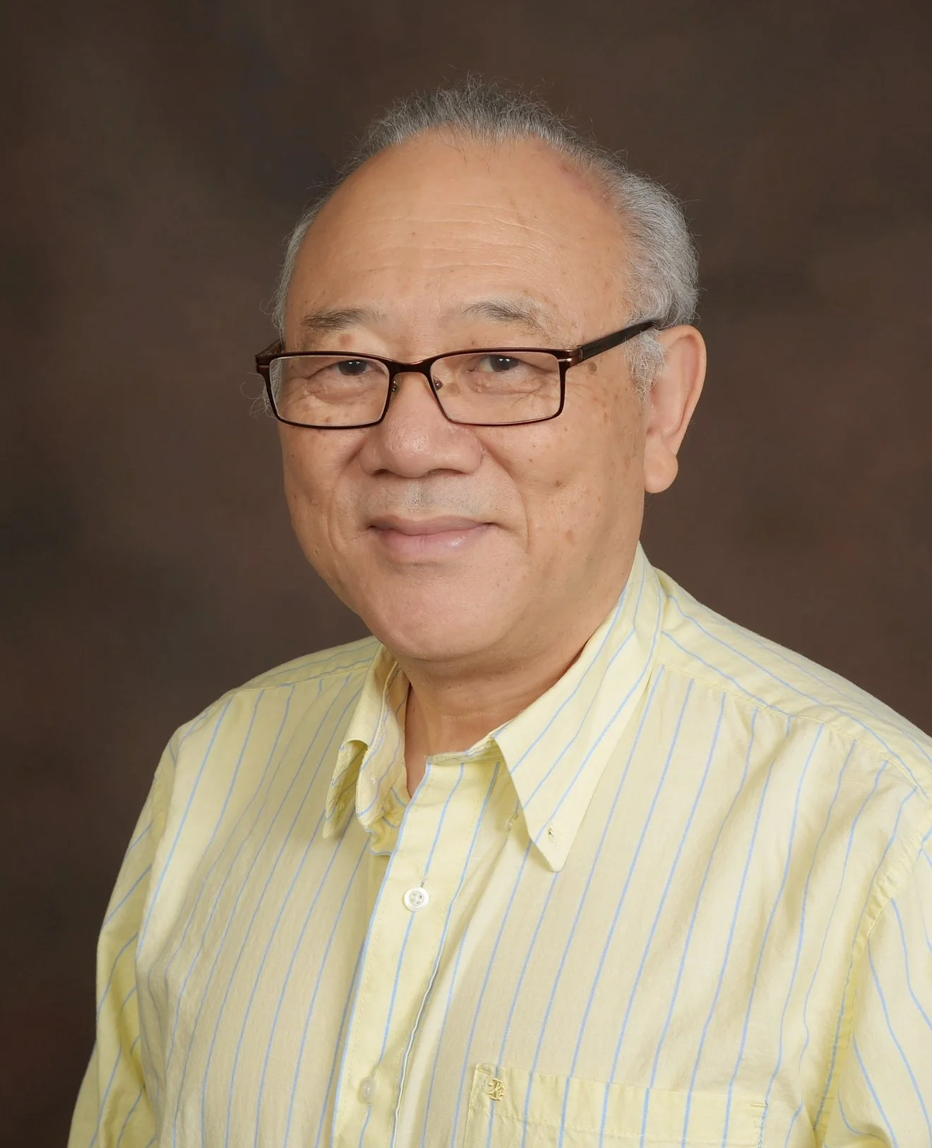 Smiling person wearing a black lace dress with earrings, posing against a neutral background.