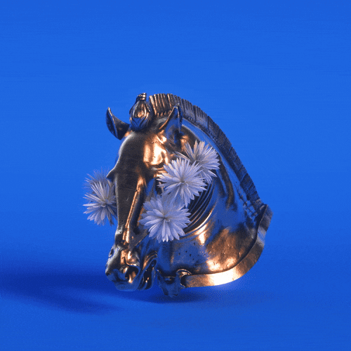A shiny gold or bronze horse head sculpture with white flowers around its face against a blue background.