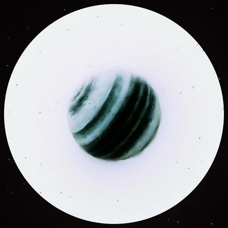 A dark-colored planet with light and dark green stripes on a white background with black specks, resembling a space scene.