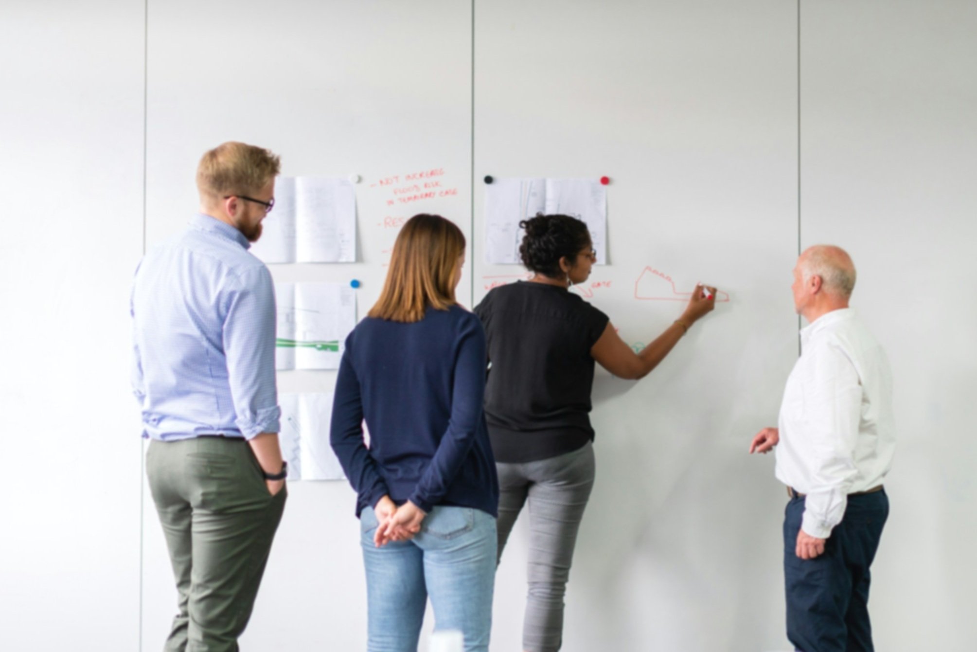 A diverse group of research staff participating in a team training session with visuals on a whiteboard.