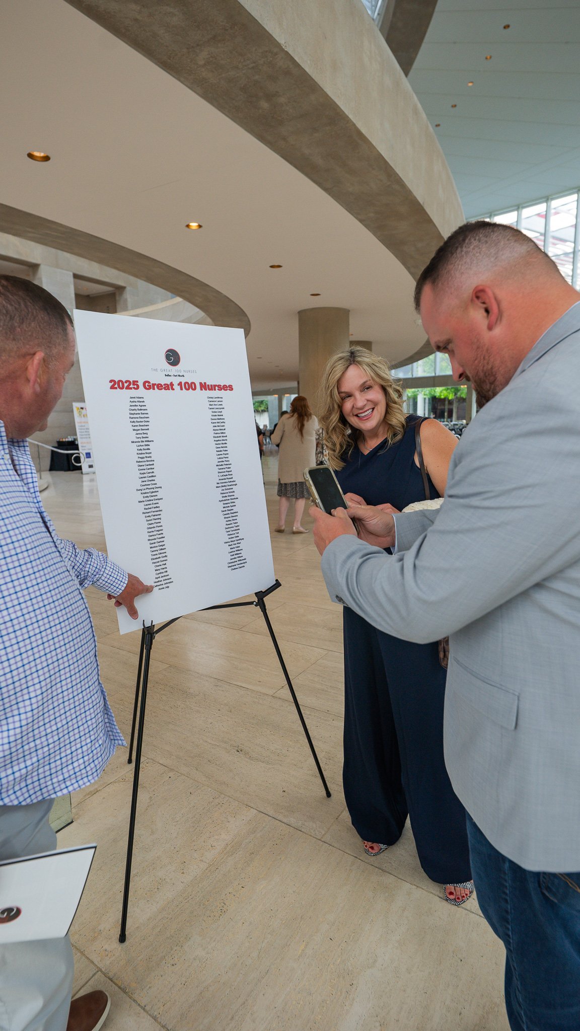 Caught in a moment of pride: a husband snapping a photo of his wife’s name among the 2025 Great 100 Nurses. She looks on, smiling—not just because her name is there, but because someone who’s seen every step of her journey is beaming behind the camer