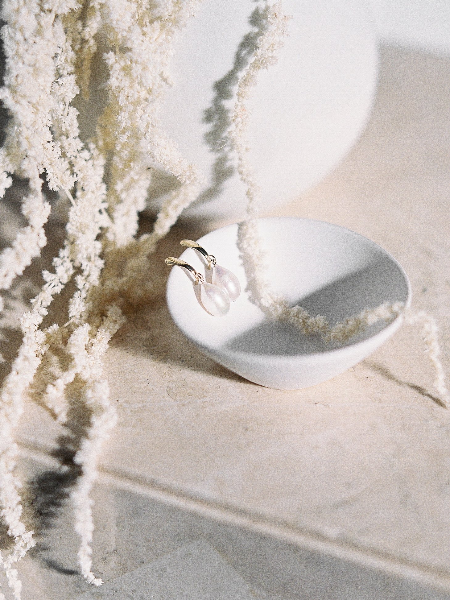 pearl and gold earrings in a white display bowl