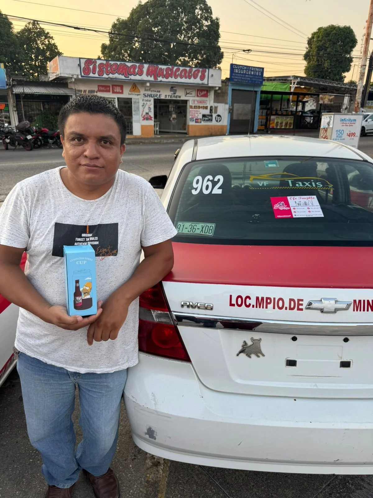 Hombre sosteniendo una caja frente a un taxi en la calle.