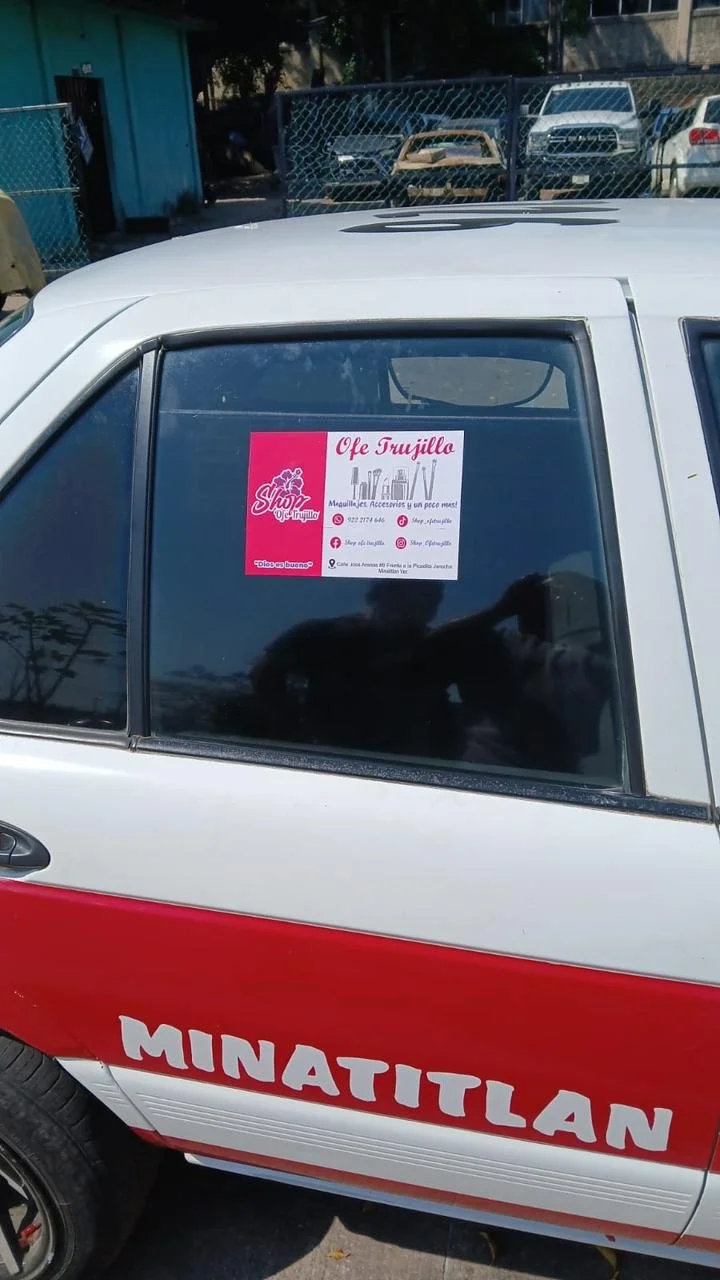 Vitral de vehículo que muestra un cartel publicitario para 'Olef Trujillo' y las palabras 'MINATITLÁN' en la parte inferior del vehículo.