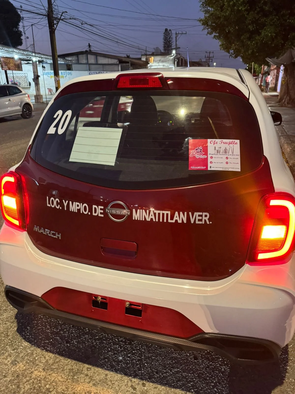 Furgoneta Nissan March con caracteres en la parte trasera que indican su ubicación en Minatitlán, Veracruz, México, y un adhesivo en el parabrisas trasero.