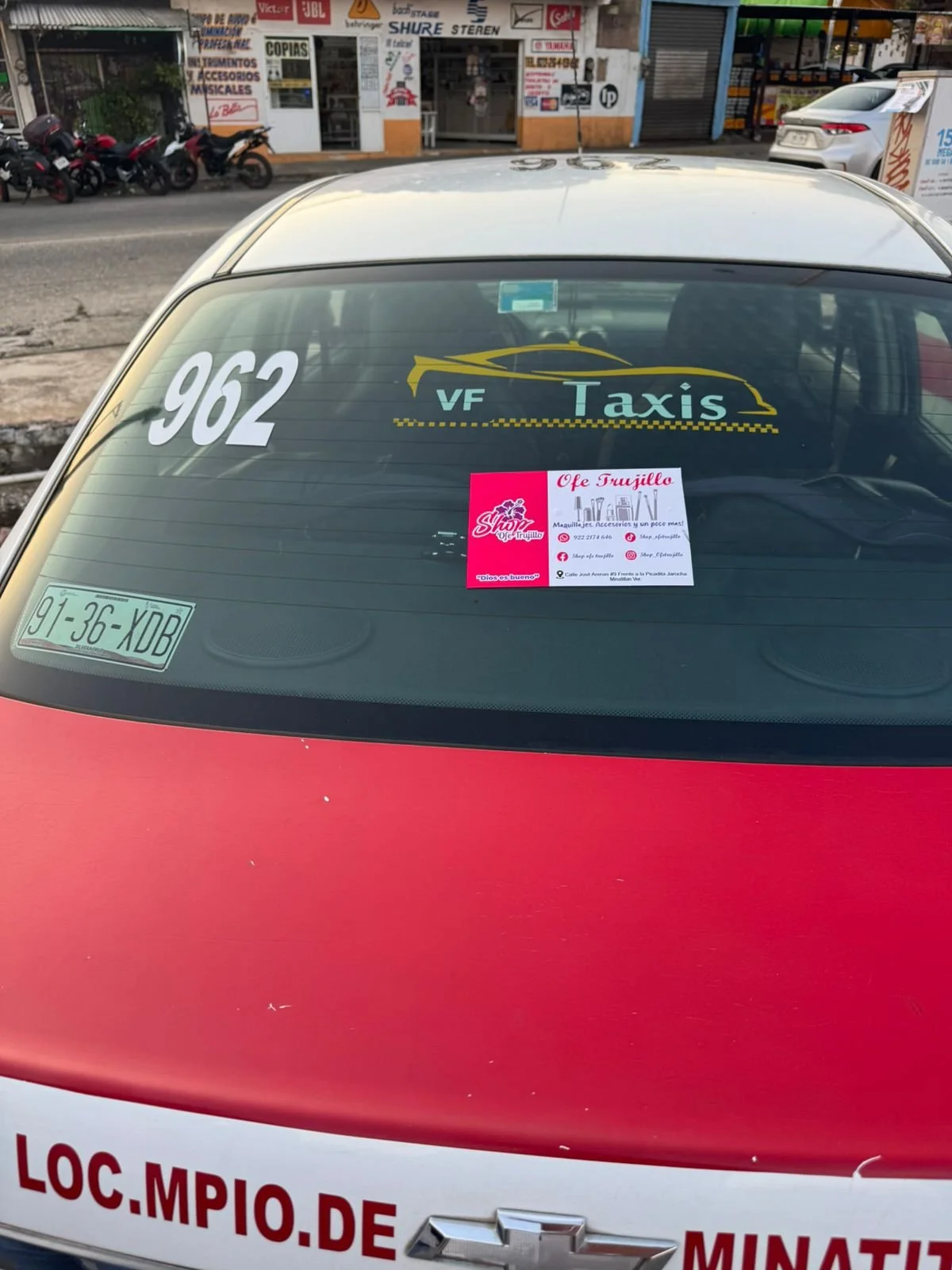 Auto de taxi con cartel publicitario en el tablero con teléfono y anuncios en la calle.