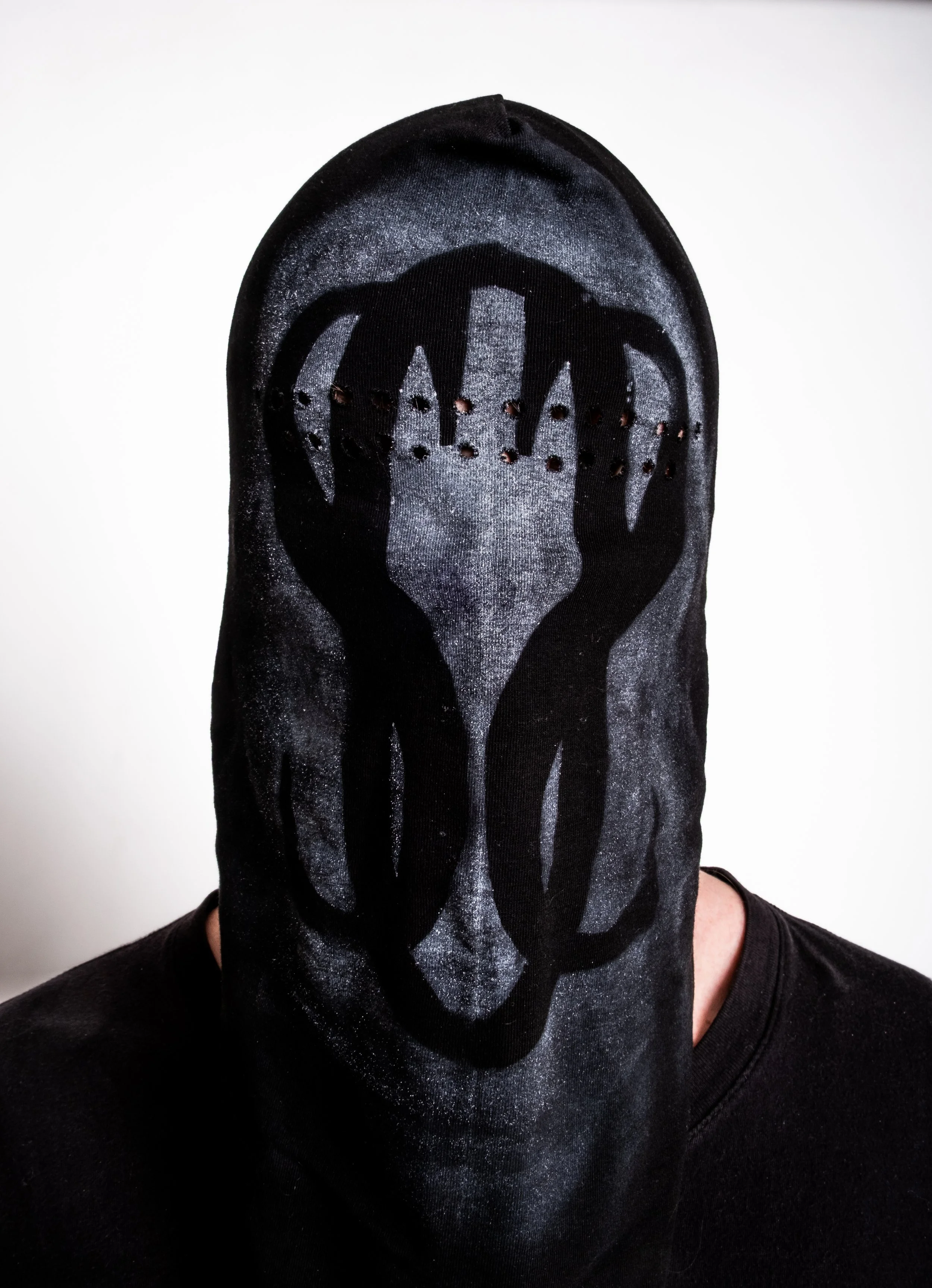 Person wearing a black mask with a graphic design covering their face.