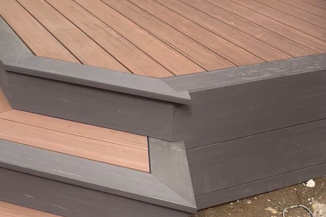 Close-up of a corner of a wooden deck with gray painted wooden trim and molding.