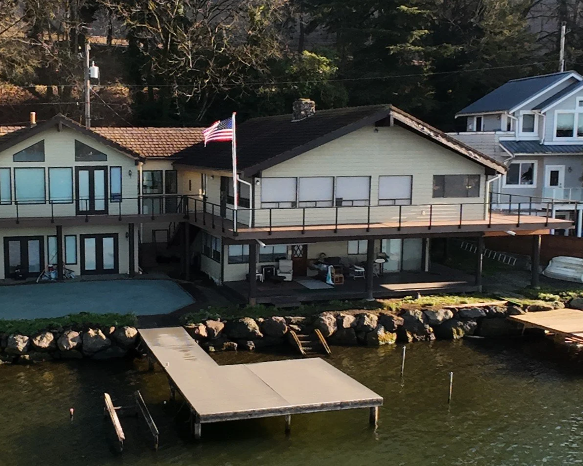 A house by the water with a dock, an American flag, and a balcony.