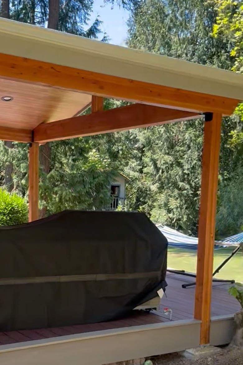 Exposed stained structural beams above a TimberTech covered deck in Sammamish WA.