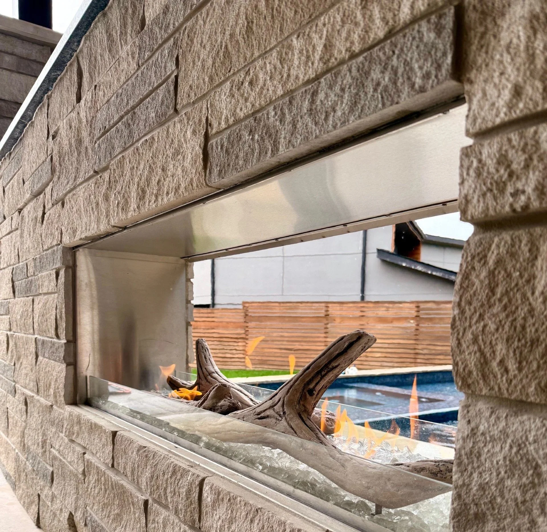 Outdoor see-through fireplace with limestone veneer and soap stone top