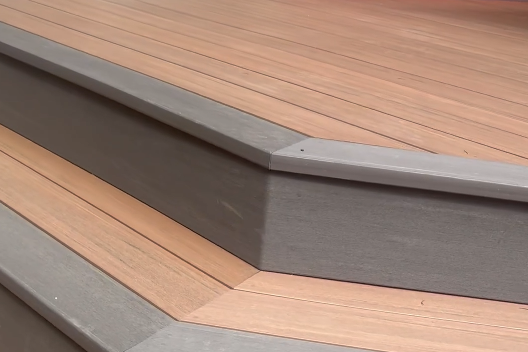 Close-up of a wooden garden bed with a raised gray border on a wooden deck.