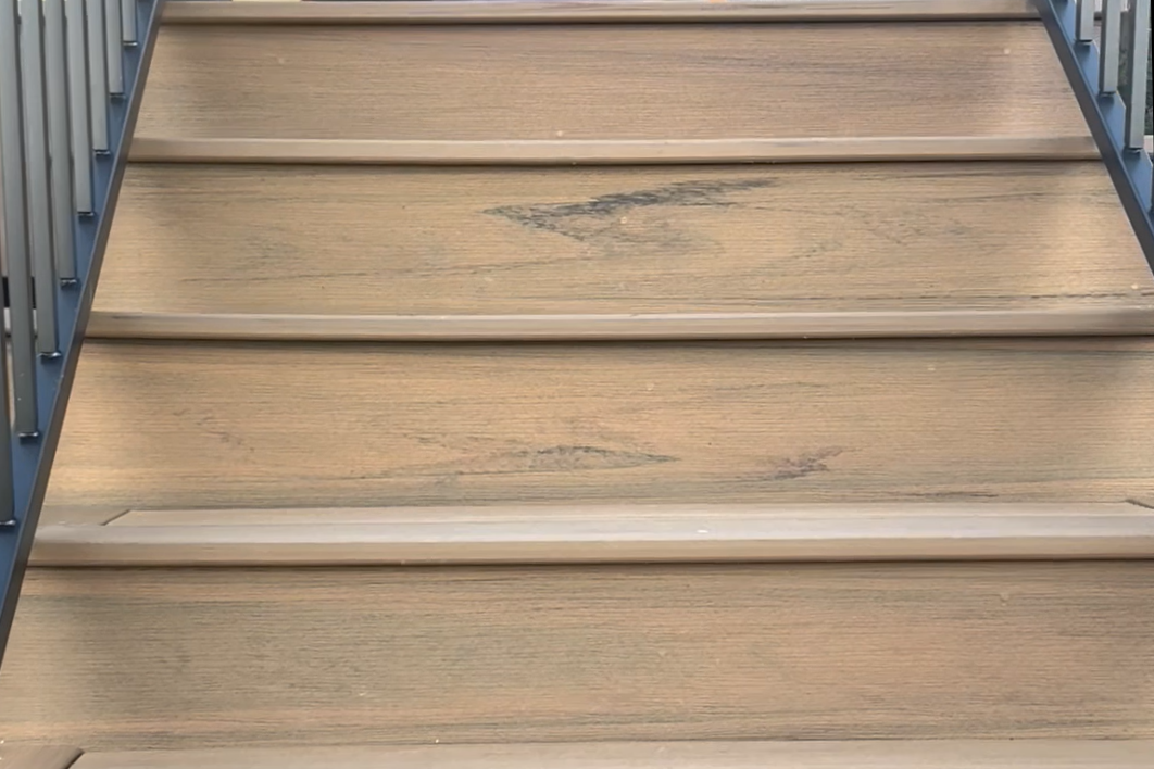 Wooden stairs with darkened and worn spots on the surface.