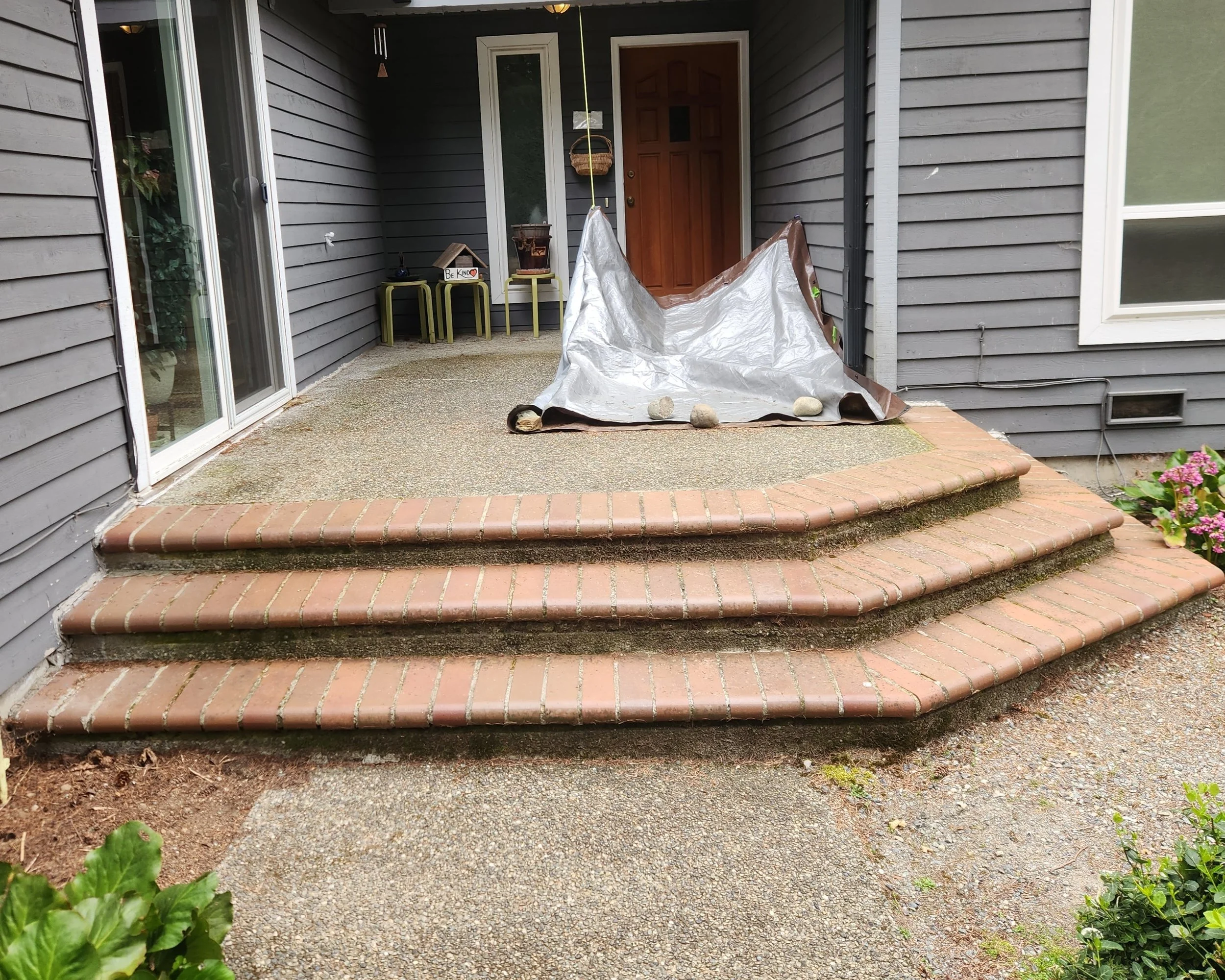 Existing concrete patio and curved masonry steps before a ground-level deck replacement in Redmond, Washington.