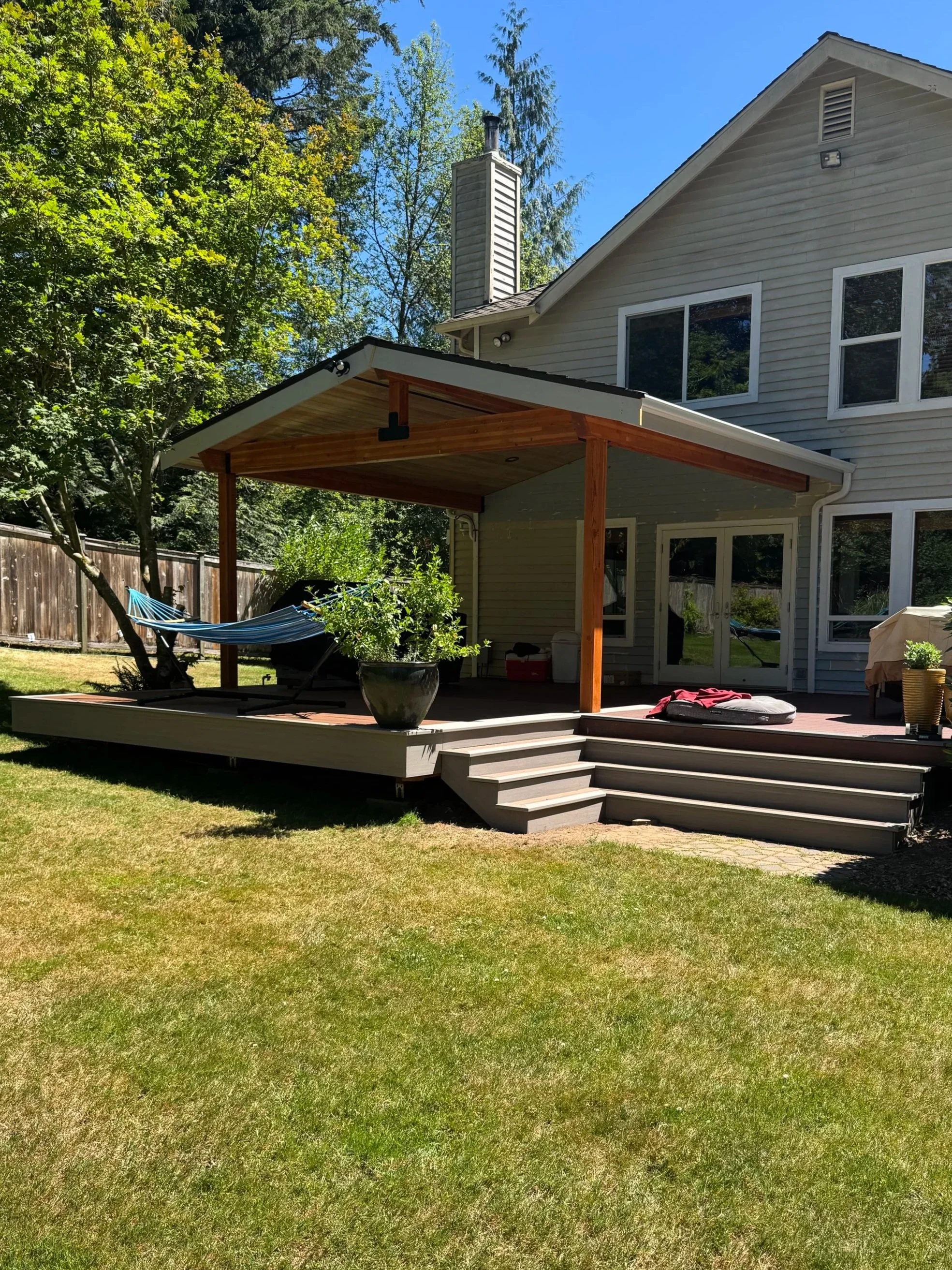 Custom covered TimberTech AZEK deck with stained wood beams and hemlock ceiling in Sammamish Washington