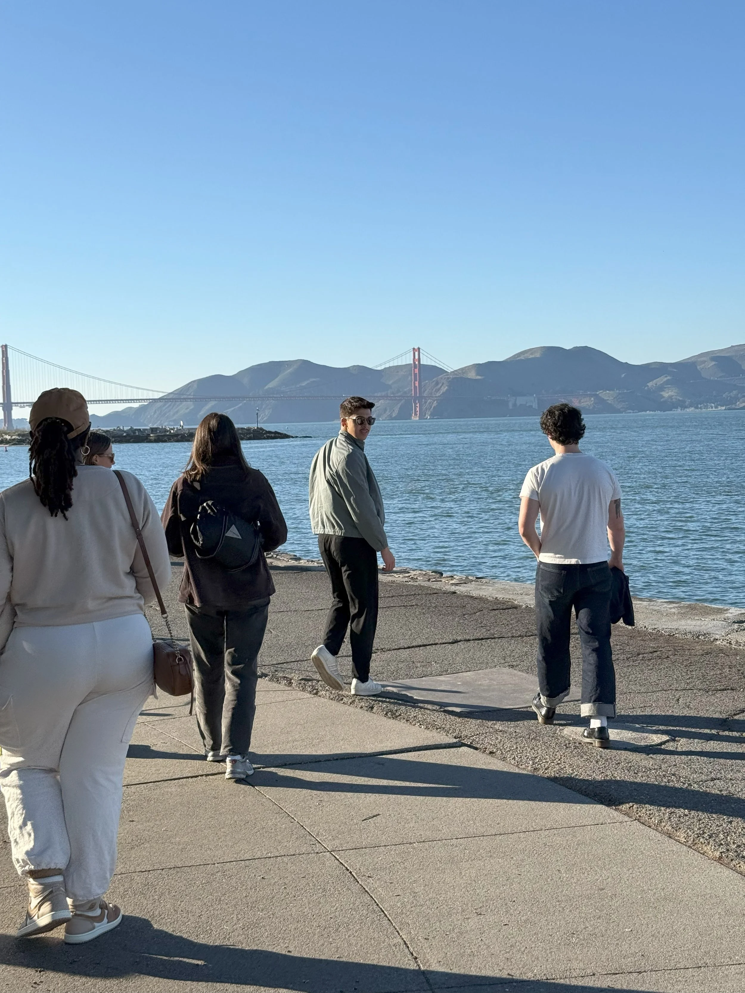 Team outing walking next to the water in San Francisco, with the Golden Gate Bridge in the background.