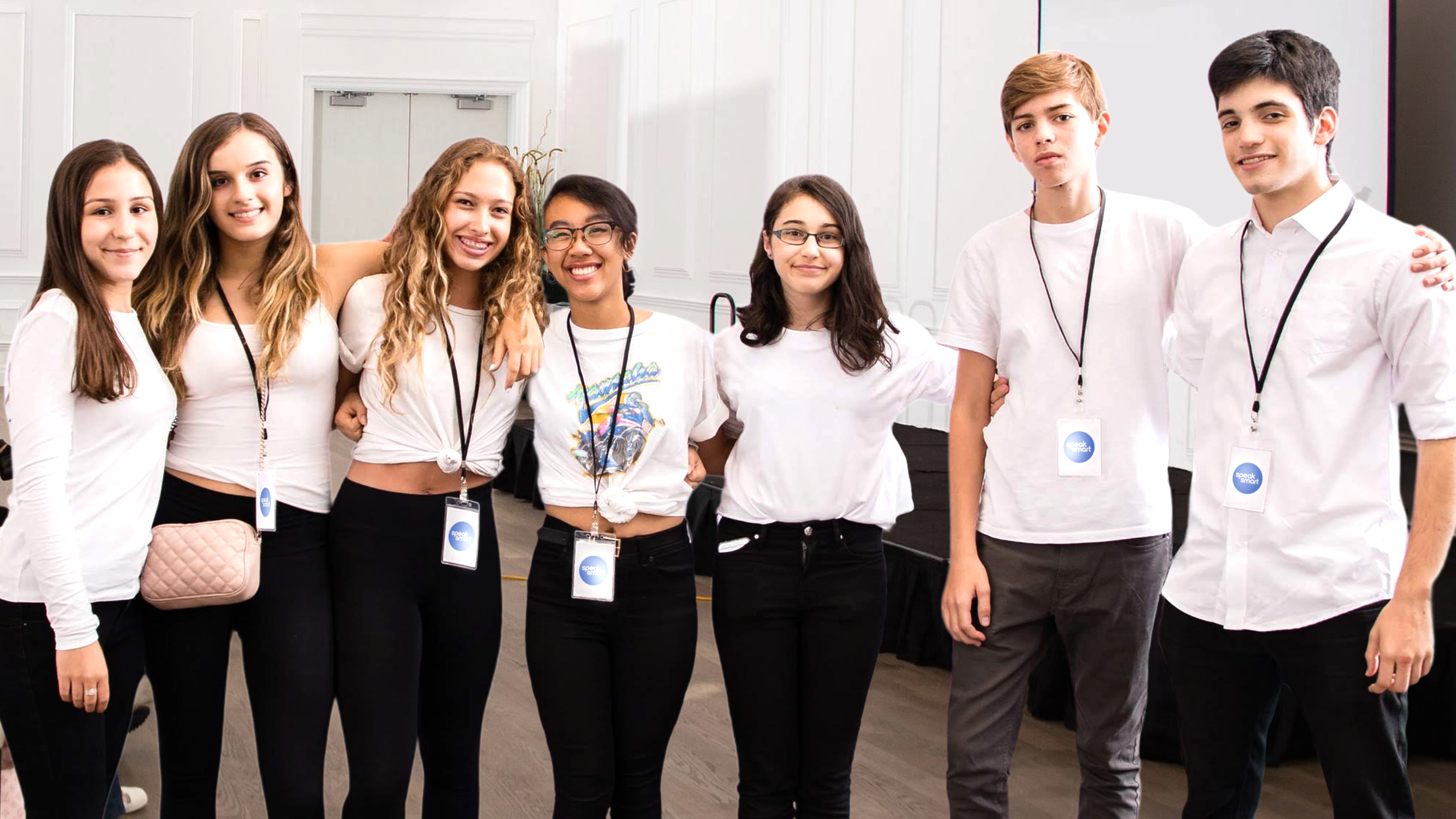 Young man giving a presentation on stage, holding a remote control, with a headset microphone, gesturing with his hand, and a colorful background projected behind him.