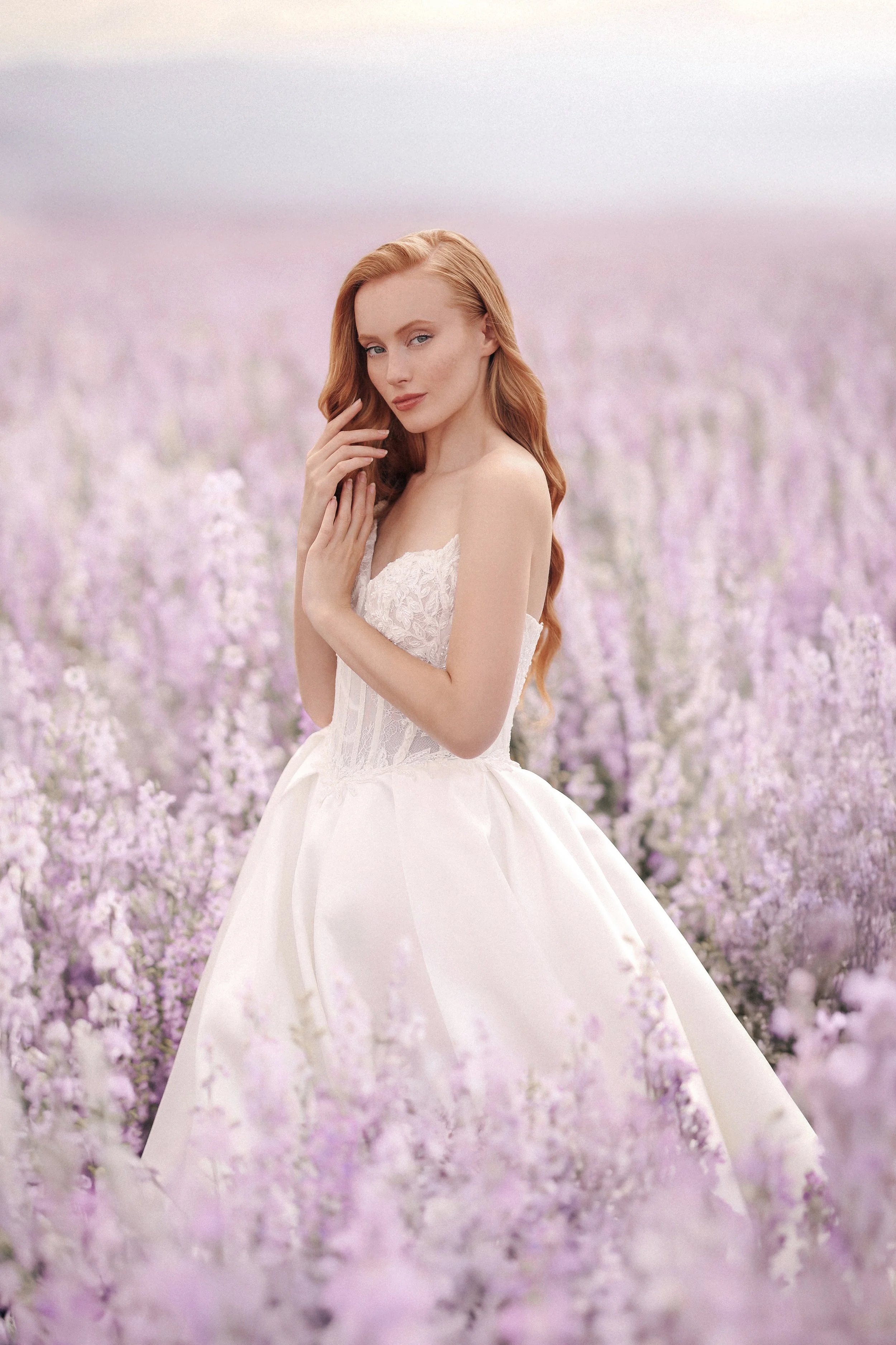 A woman in a white dress standing in a field of purple flowers.