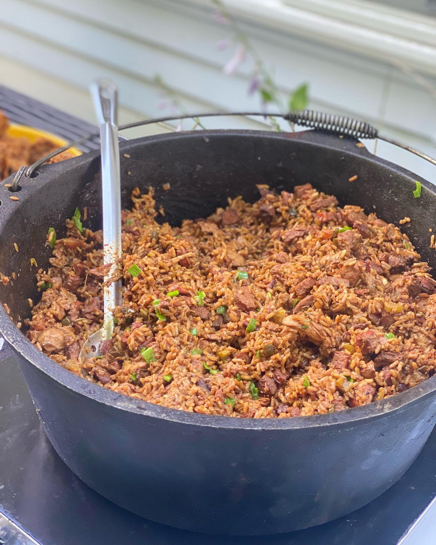 Large pot of jambalaya with a serving spoon on a table.