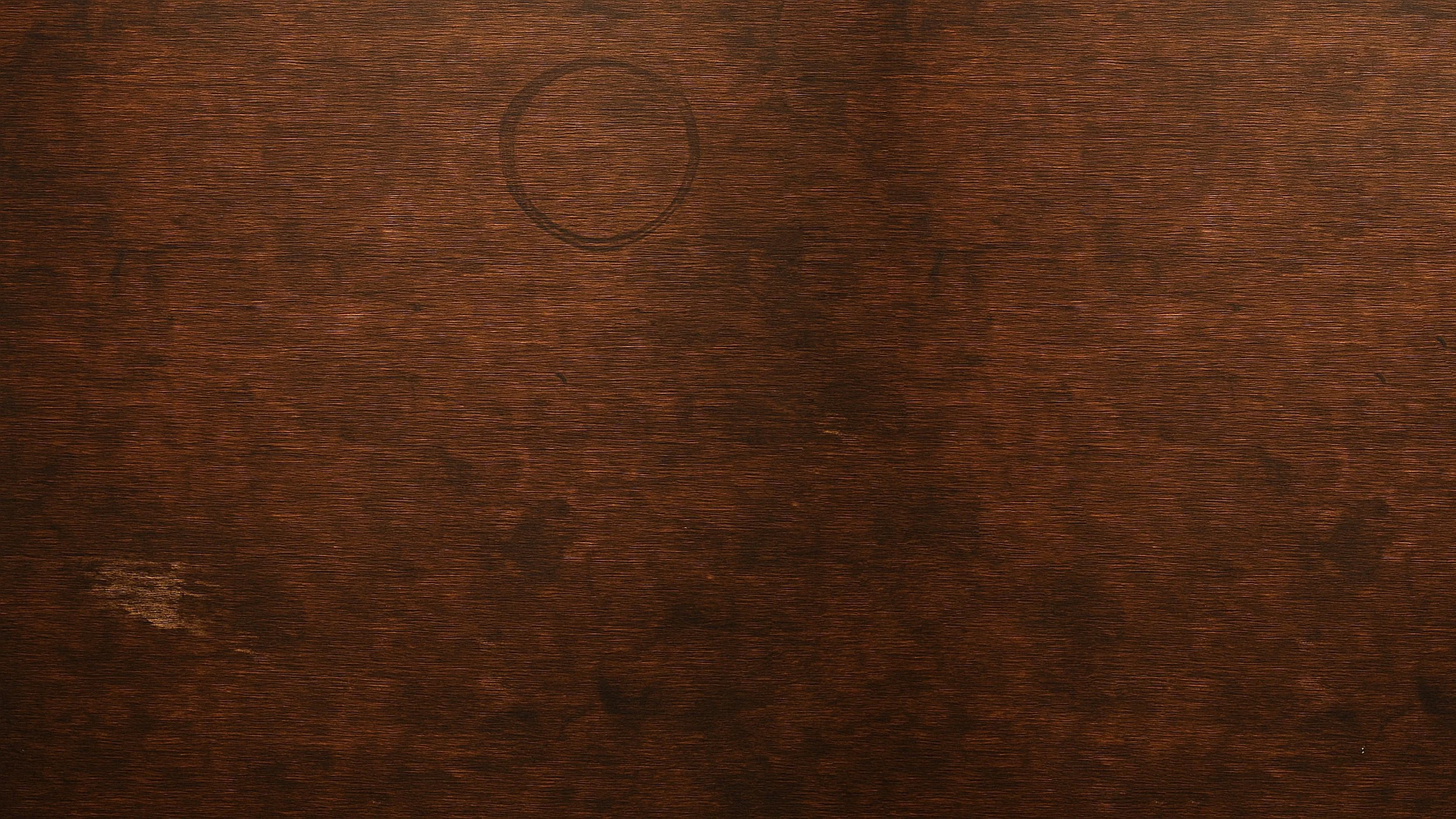 A wooden surface with visible grain and a circular mark.