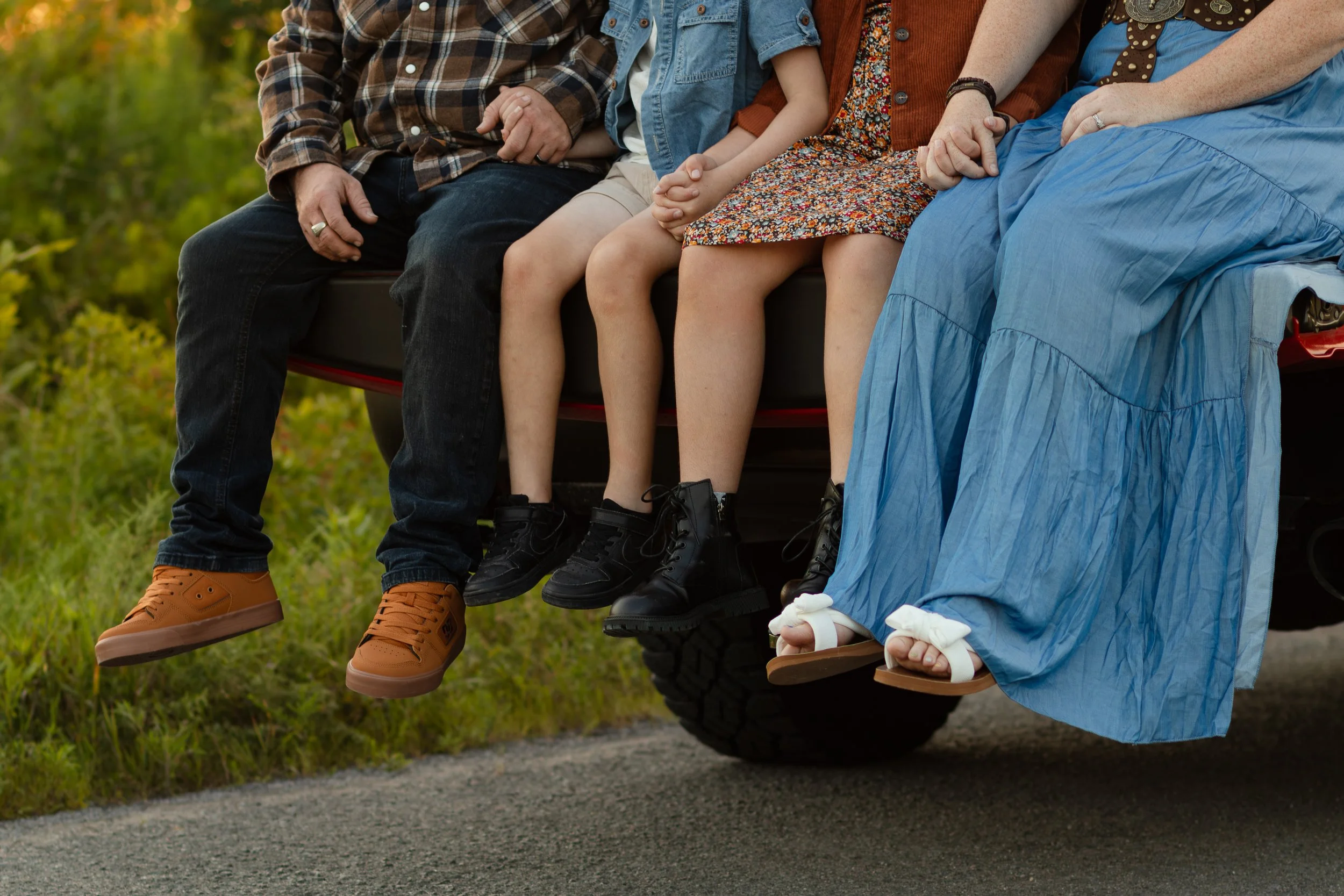 People sitting on a vehicle with their legs hanging down, holding hands, in a natural outdoor setting.