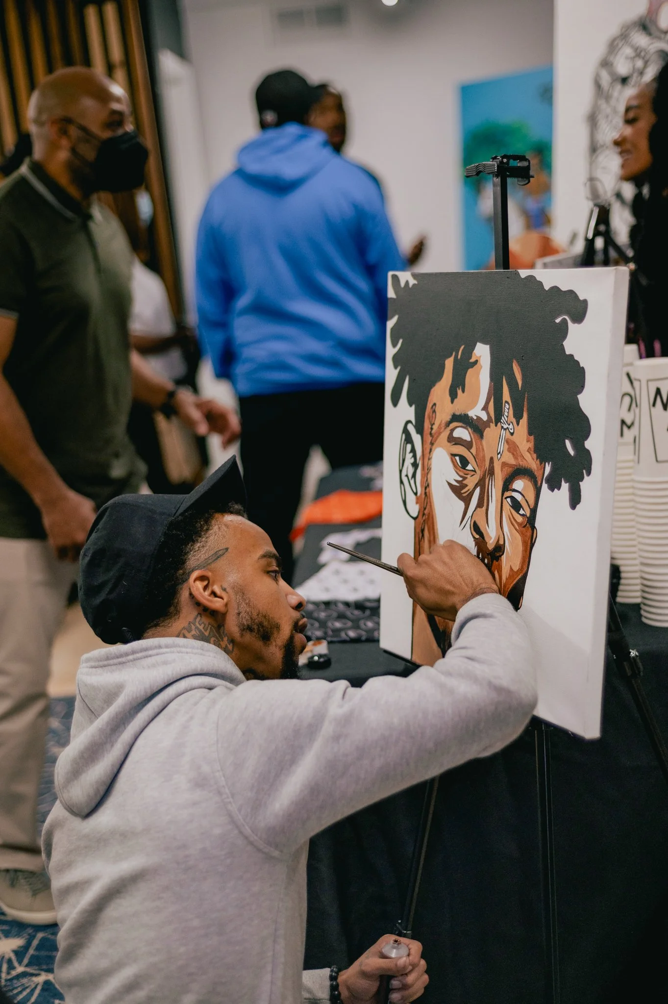 photo of black boy art show exhibition featuring young black male artist painting an image of 21 savage. photo taken by black woman professional event photographer in metro detroit michigan