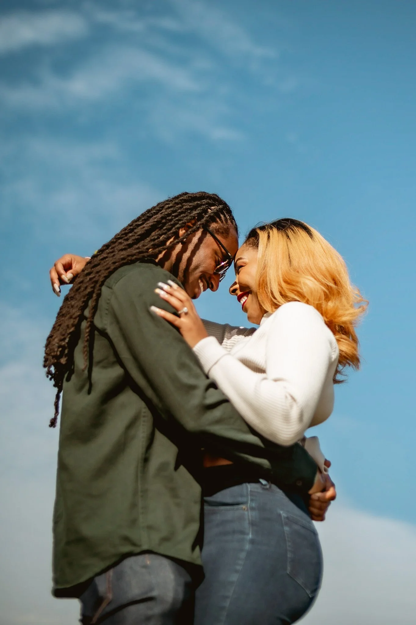 photo of young black married couple taken against blue sky backdrop. photo was taken by black woman photographer in metro detroit area with a photography studio in pontiac, michigan