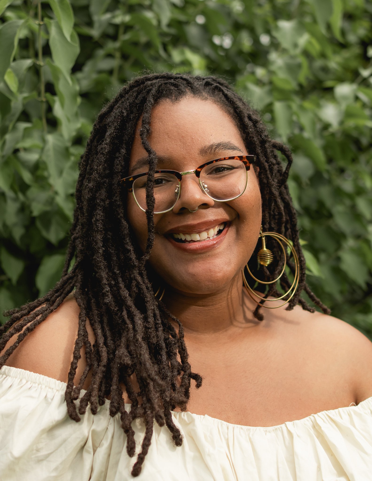self portrait of a professional event photographer who serves the metro detroit area. photo is of a young black woman wearing glasses and smiling