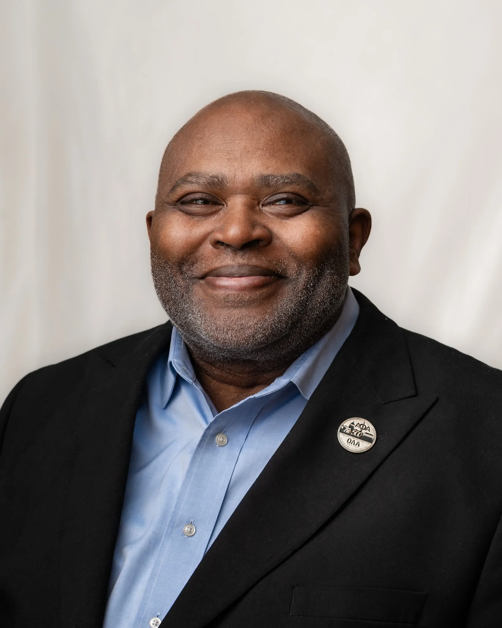 photo is a traditional headshot of an older, plus size black man who is smiling and bald. headshot was taken by a black woman photographer in pontiac michigan who serves the metro detroit area from her photo studio in pontiac.
