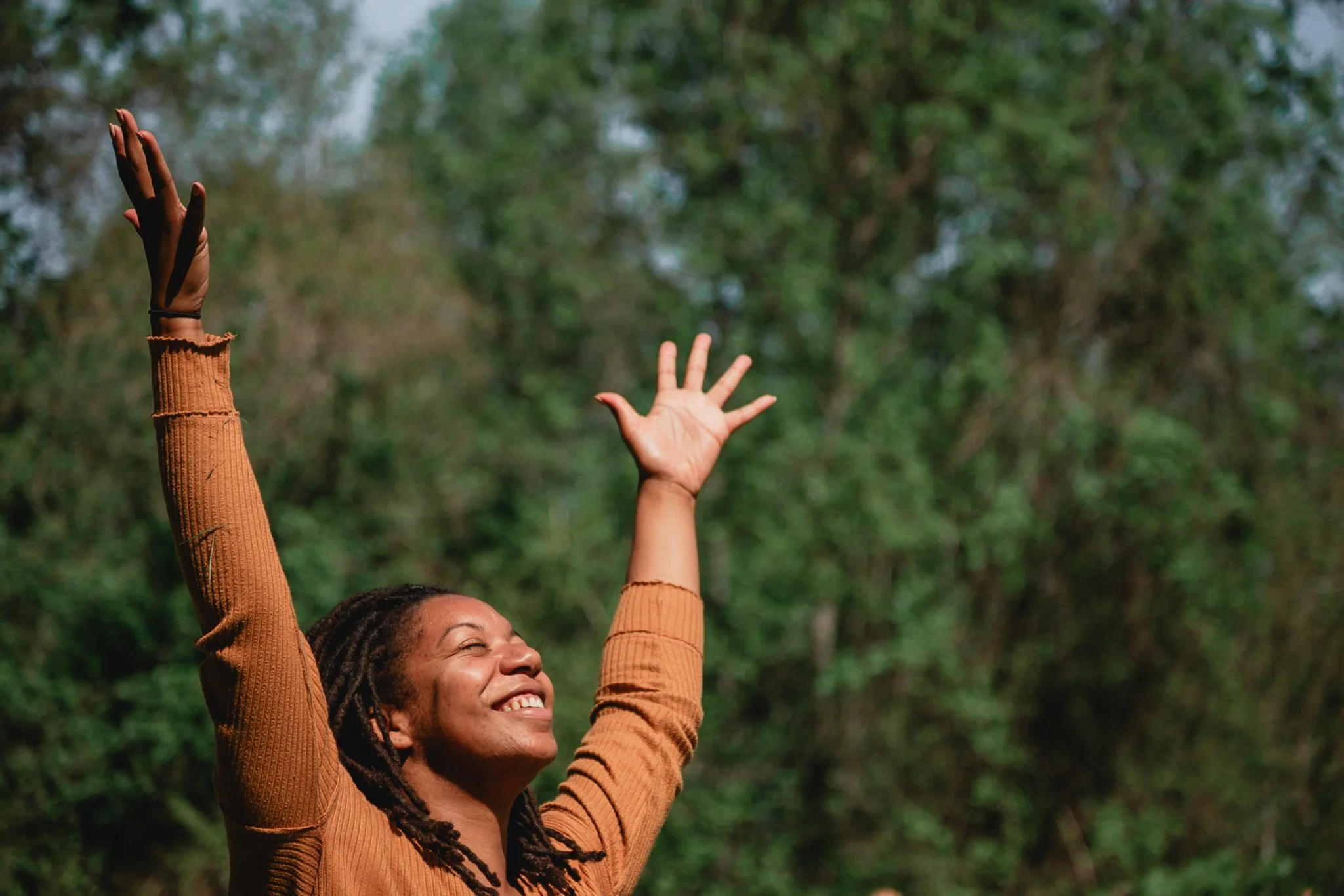 young, black woman yoga instructor teaching outdoor yoga class while in tree pose. photo taken by black woman corporate event photographer in metro detroit michigan