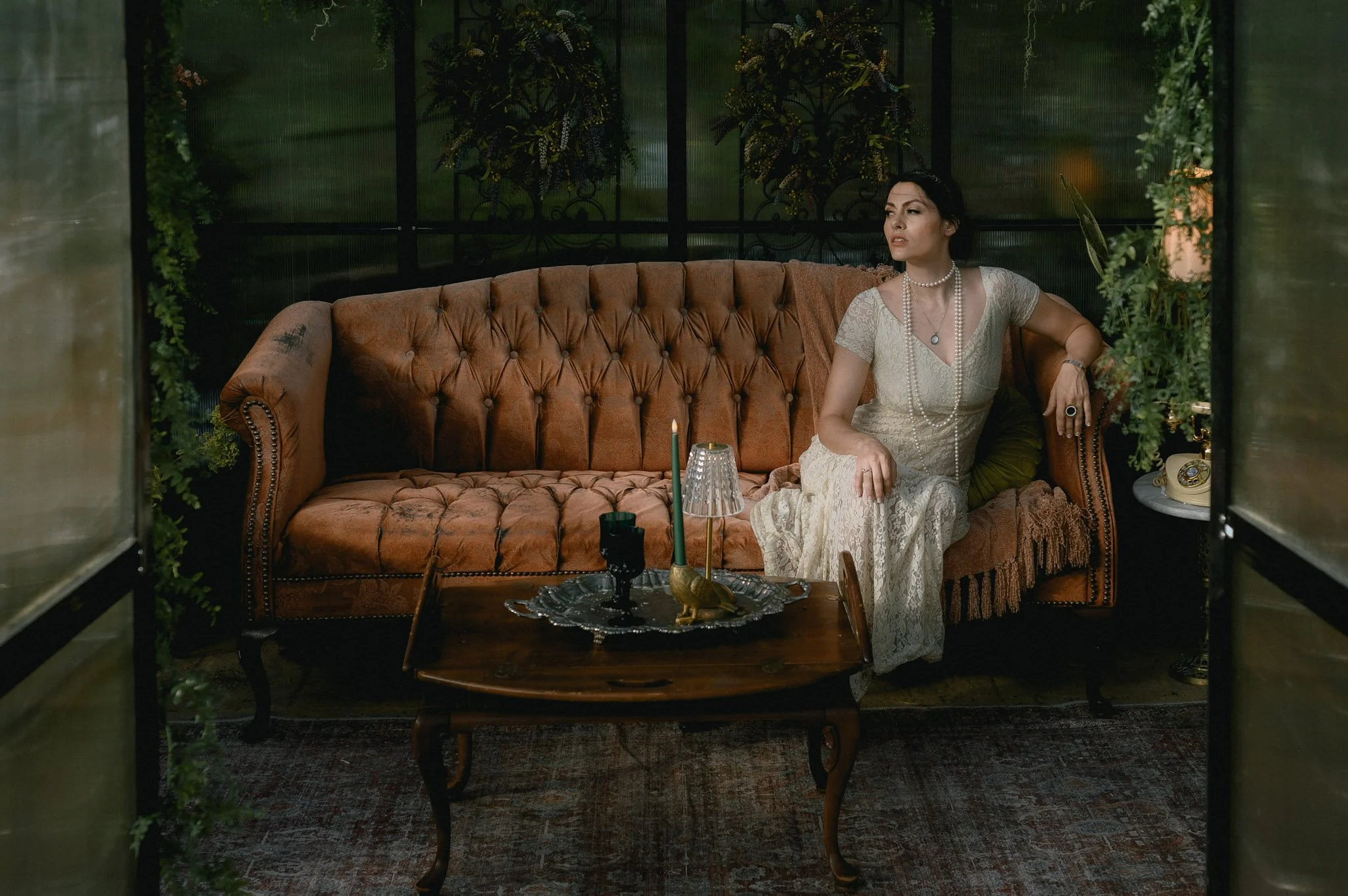 bridal portrait photography showing bride sitting on vintage couch wearing vintage weddign gown and pearls