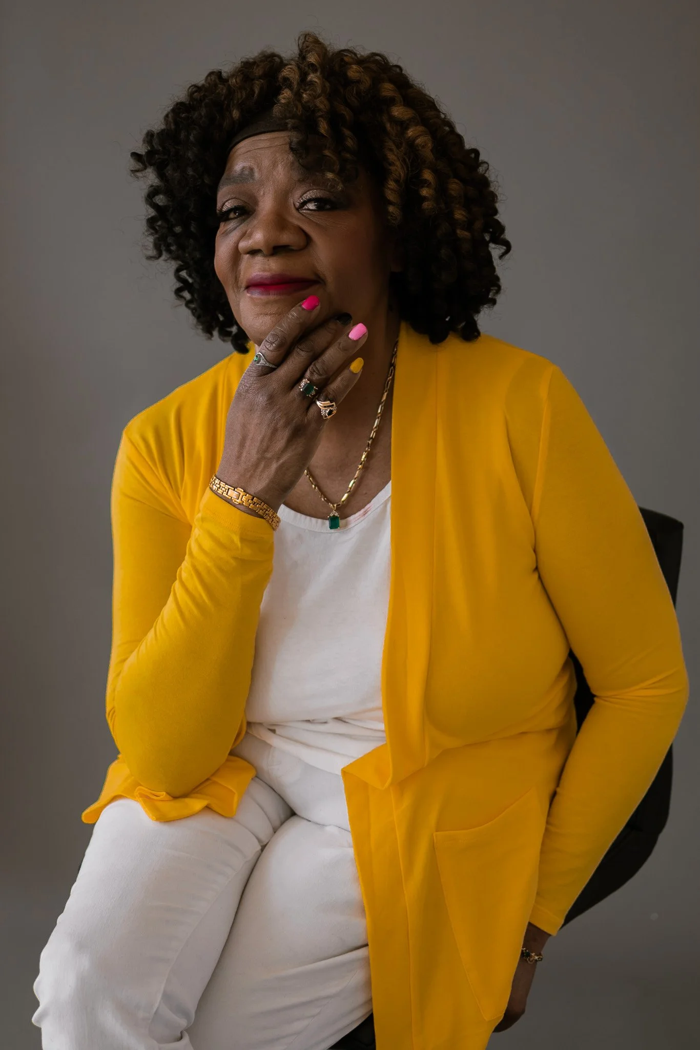photo of older black woman with curly hair and yellow sweater. photo is from a birthday photoshoot celebrating a senior citizen. photo was taken by a black woman photographer in southeast michigan who serves metro detroit.
