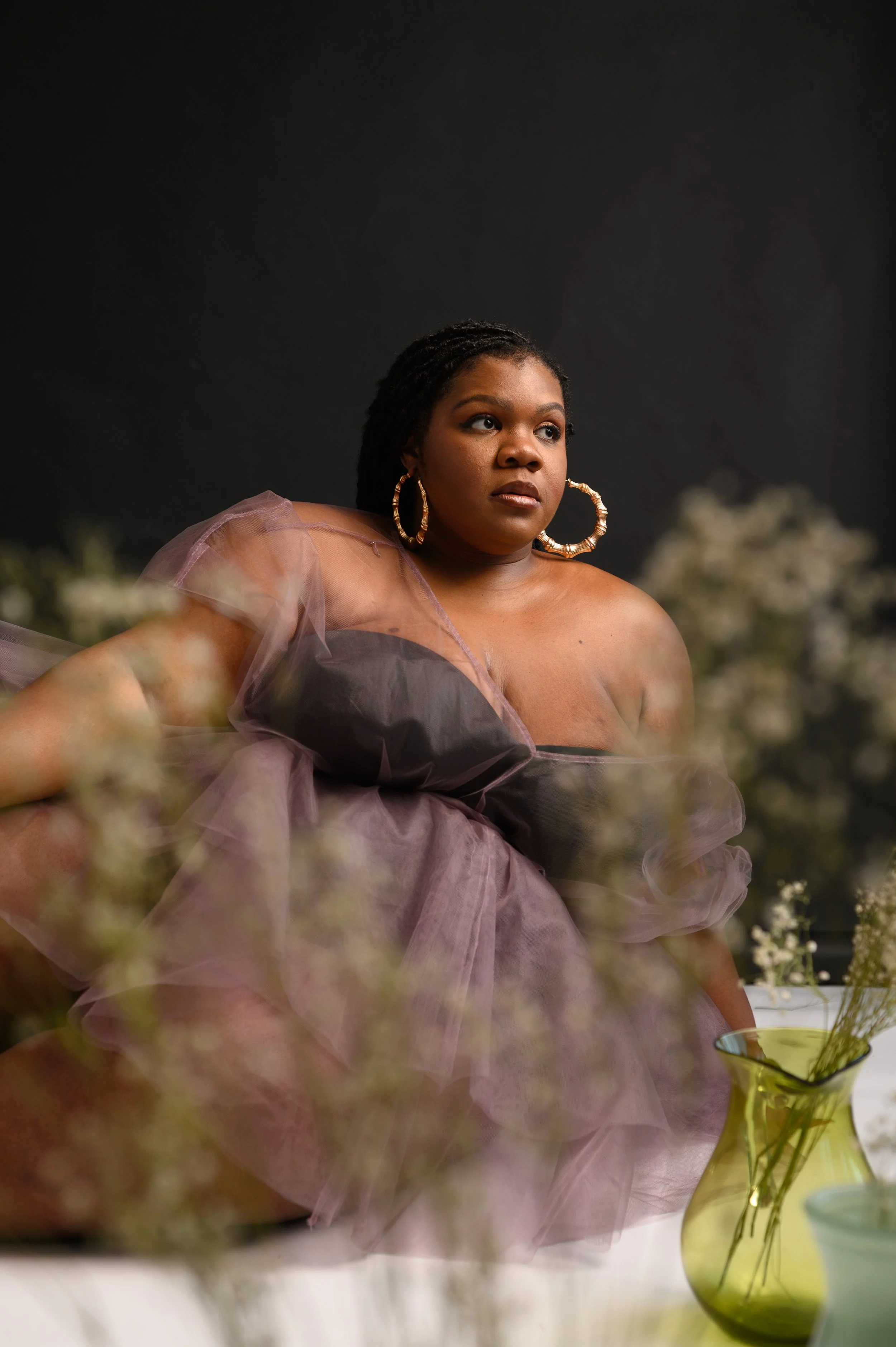 plus size black woman posing with flowers in studio photoshoot with black background with black woman photographer in Newport News 