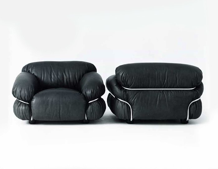 Black leather armchair and matching ottoman with metallic accents in a minimalistic setting.