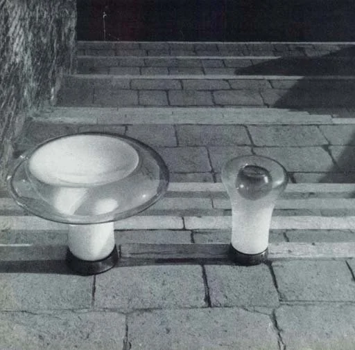 Saffo and Lesbo lamps for Artemide (1967): The two lamps are made of blown glass, shaded, whose plastically soft shape rests on a small cylindrical metal base.