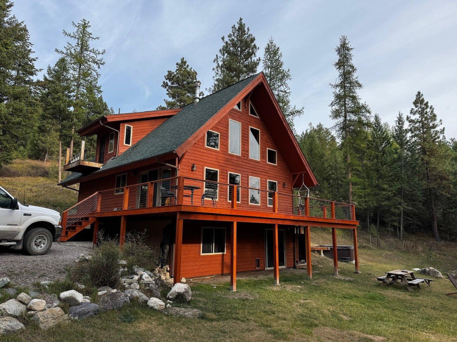 Red stained wooden log cabin in Montana forrest with trees