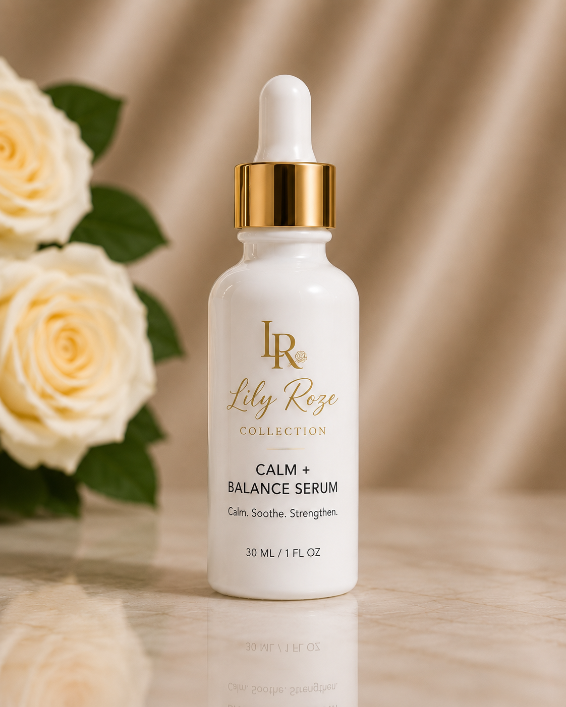 A white cosmetic bottle with a gold cap and dropper, labeled 'Lily Roze Collection Calm + Balance Serum,' placed on a marble surface with cream-colored roses and a beige satin background.