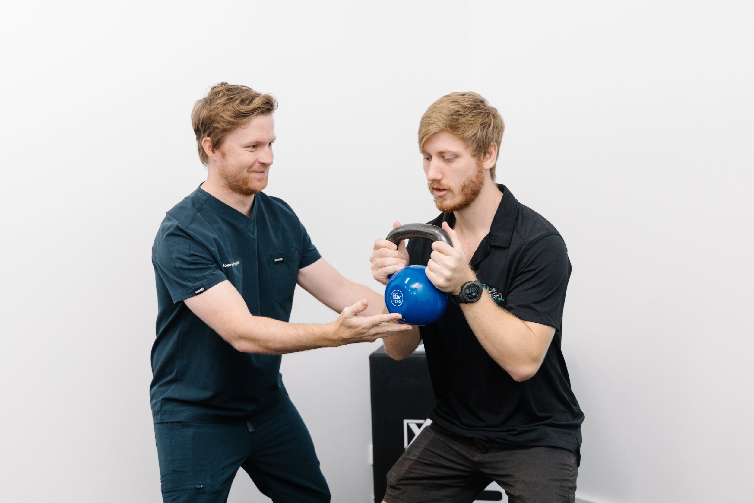 Physiotherapist guiding a patient through a kettlebell strength exercise at Move Right Physio Dakabin