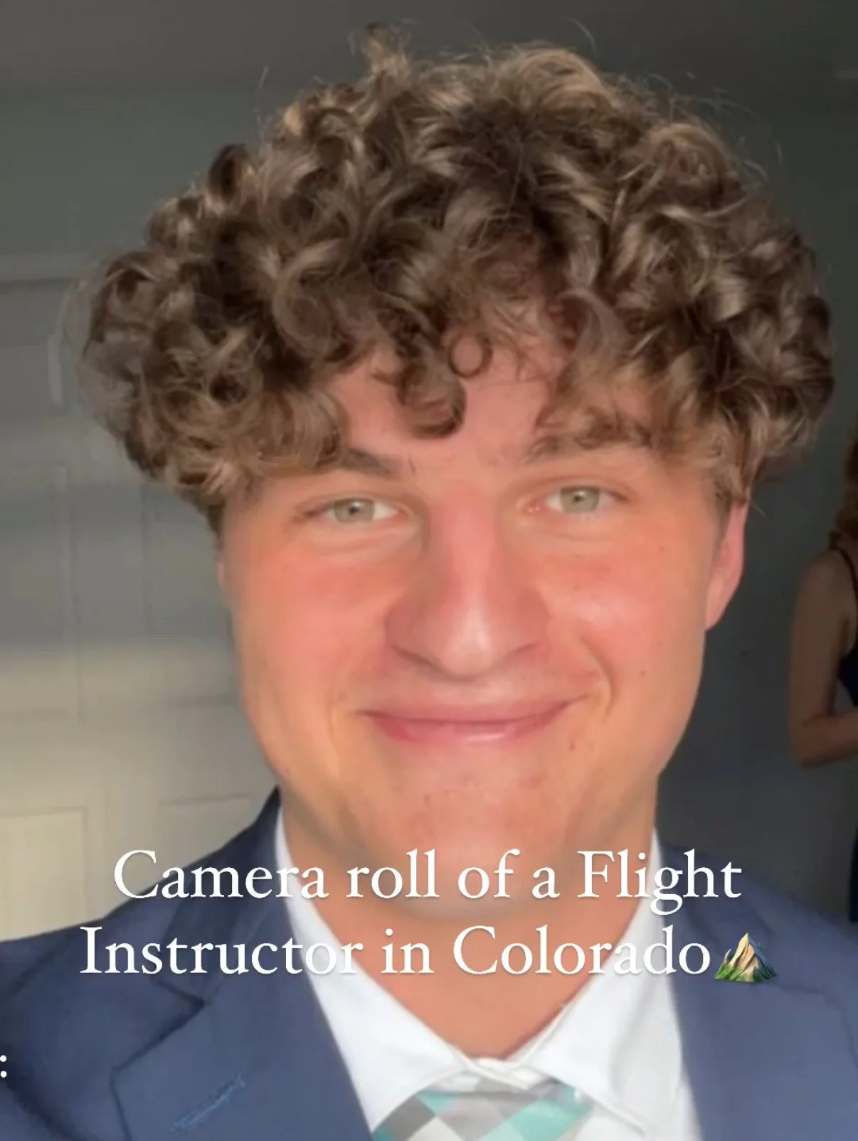 Smiling person with curly hair in formal attire, caption reads "Camera roll of a Flight Instructor in Colorado" with a mountain emoji.