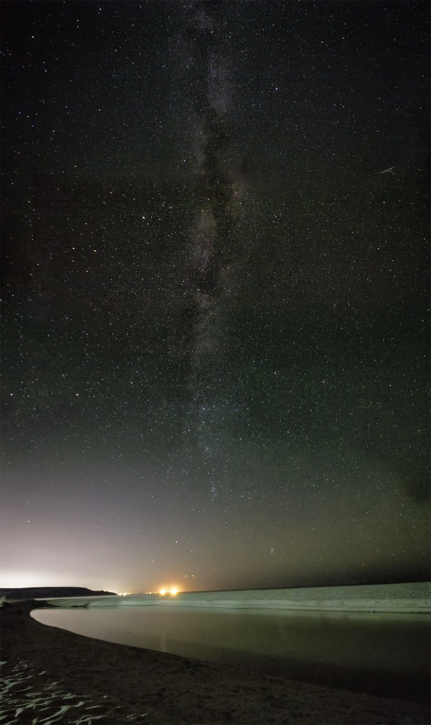 A dark sky, starry night over a calm ocean,  with little light pollution visible