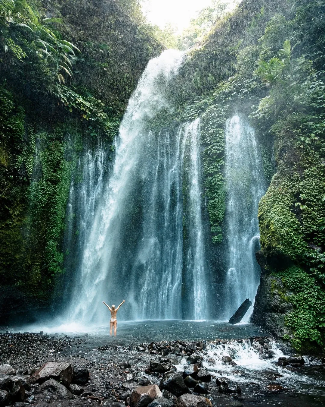 Traveller swimming beneath Tiu Kelep Waterfall in North Lombok
